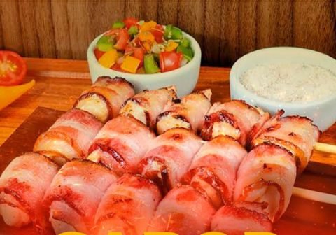 Espetinhos de queijo enrolados em bacon, dourados na grelha