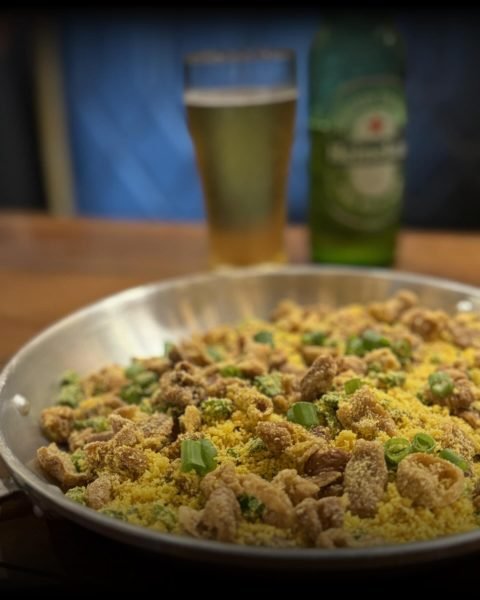 Farofa de tripa na panela ao lado de cerveja gelada