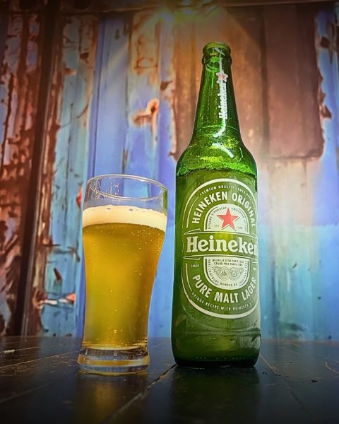 Cerveja servida no copo ao lado da garrafa gelada